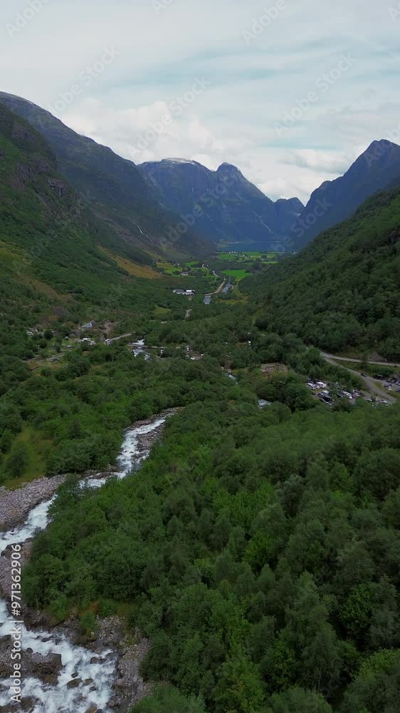 Drone 4K breathtaking aerial view of a lush green valley with a flowing river at its center in Norway, Portrait Orientation Drone 4K breathtaking aerial view of a lush green valley with a flowing river at its center in Norway, Portrait Orientation