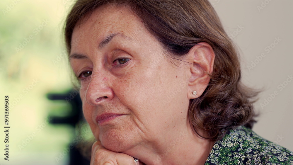 Fototapeta premium Side profile of an elderly woman with a thoughtful expression, resting her chin on her hand. natural light enhances her reflective and serene demeanor, highlighting her wisdom and calmness