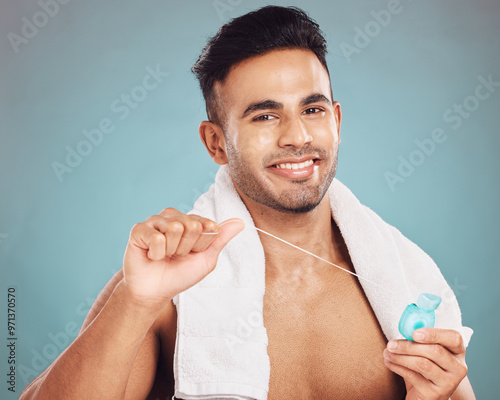 Studio, portrait and man with dental floss for oral, gum health and wellness with cleaning for fresh breath. Male model, teeth and string by blue background for mouth, gingivitis and hygiene care