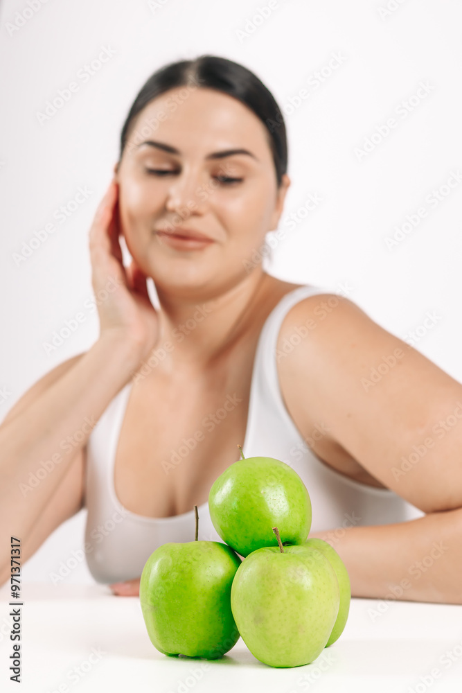 Young woman on a light background next to fresh green apples. Perfect for promoting healthy eating, highlighting the freshness and naturalness of your choice. Young woman on a light background next to fresh green apples. Perfect for promoting healthy eating, highlighting the freshness and naturalness of your choice.