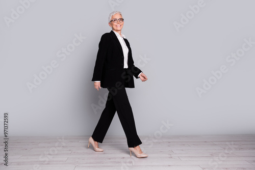 Full length photo of charming cheerful successful senior lady wear stylish black costume isolated on grey color background