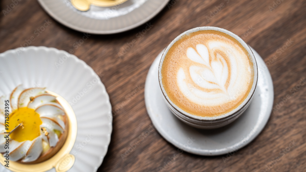 Latte art in cappuccino coffee cup at cafe table. Closeup of rosetta flower drawing in foam. hot latte coffee put on table in cafe restaurant or coffee shop, drink breakfast in the morning day Latte art in cappuccino coffee cup at cafe table. Closeup of rosetta flower drawing in foam. hot latte coffee put on table in cafe restaurant or coffee shop, drink breakfast in the morning day