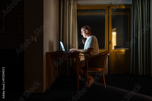 Riga, Latvia A man works at a desk late at night illuminted by a computer.