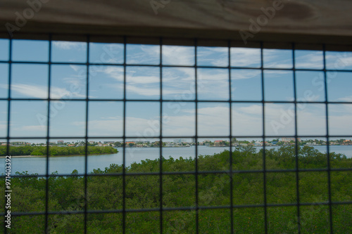 High Wide view frame  through screen mesh from observation tower towards Boca Ciega Bay. Towards an island with green trees. Bright sunshine with blue sky and white clouds at Millennium Park nature tr photo