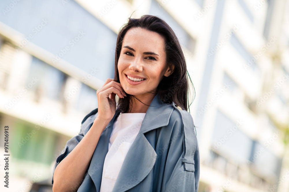 Photo of charming positive woman wear grey trench smiling enjoying wind blowing outdoors urban city street Photo of charming positive woman wear grey trench smiling enjoying wind blowing outdoors urban city street