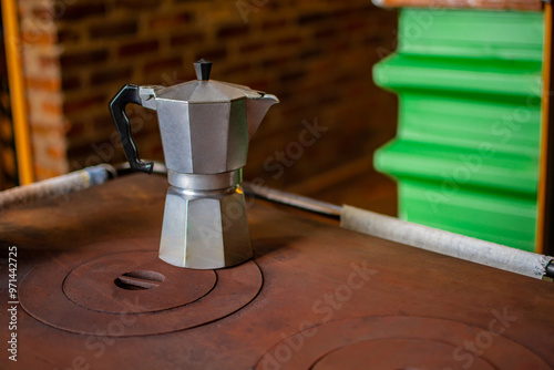 Italian metal coffee maker preparing coffee on top of wood burning stove in rustic wooden chalet home photo