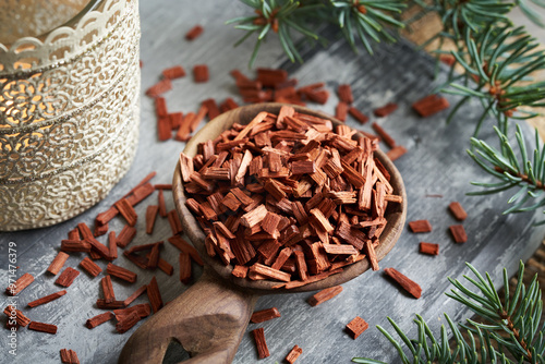 Red sandalwood chips - ingredient for essential oils, with a candle and spruce tree photo