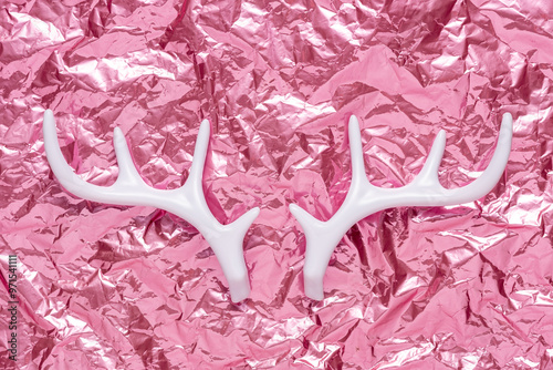 White reindeer anthlers on pink crumpled foil background. Minimal holiday concept. photo