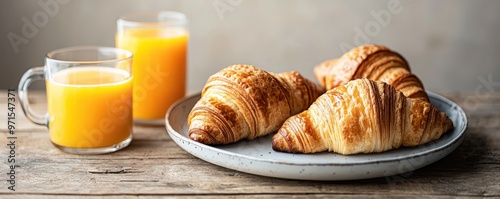 Freshly baked croissants on a plate with a glass of orange juice, perfect for a delightful breakfast or brunch setting. photo