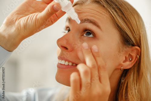 A woman is carefully applying eye drops to effectively hydrate her eyes and significantly enhance comfort photo