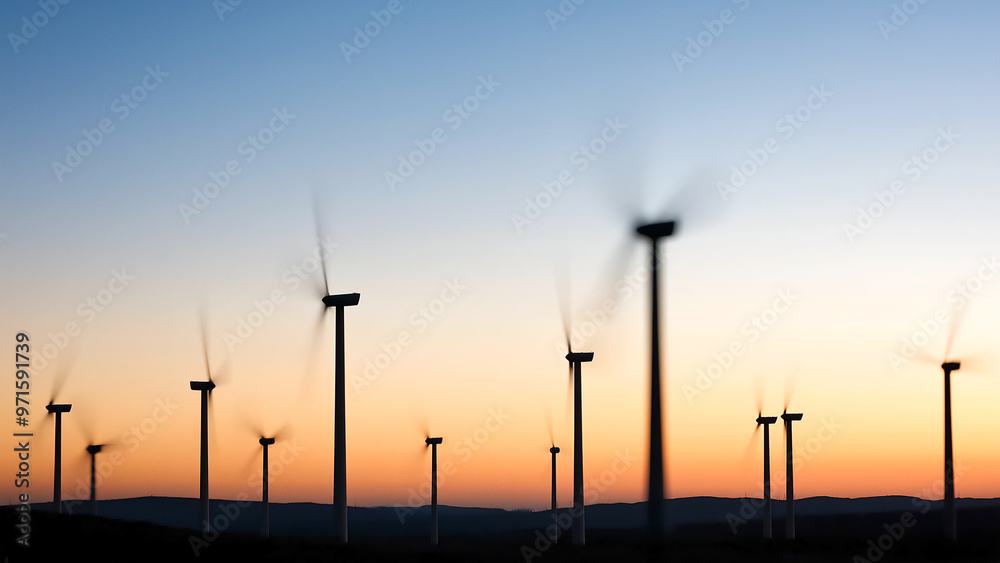 Obraz premium A row of wind turbines spinning against the backdrop of dusk, creating an abstract and atmospheric scene with blurred motion.