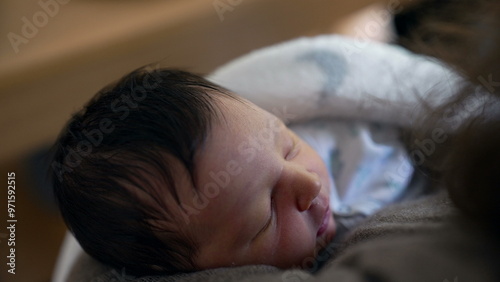 Close-up of a newborn baby sleeping in mother’s arms, showcasing the peace and security of early life. the tender bond and nurturing care provided during early motherhood