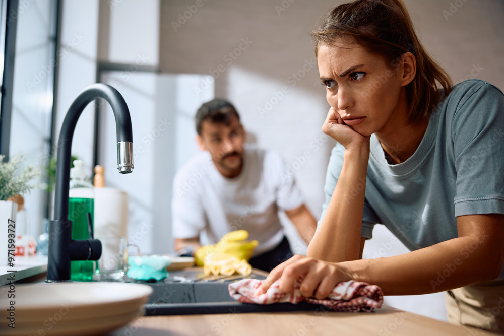 Upset woman feeling mad at her boyfriend while doing the dishes in kitchen. Upset woman feeling mad at her boyfriend while doing the dishes in kitchen.