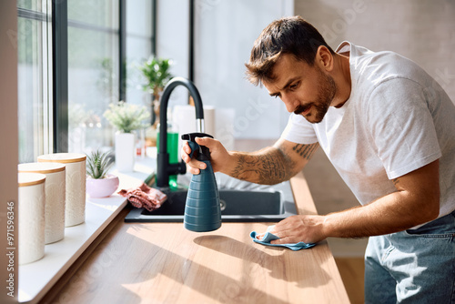 Fotografie Young man wiping kitchen counter while cleaning  house.