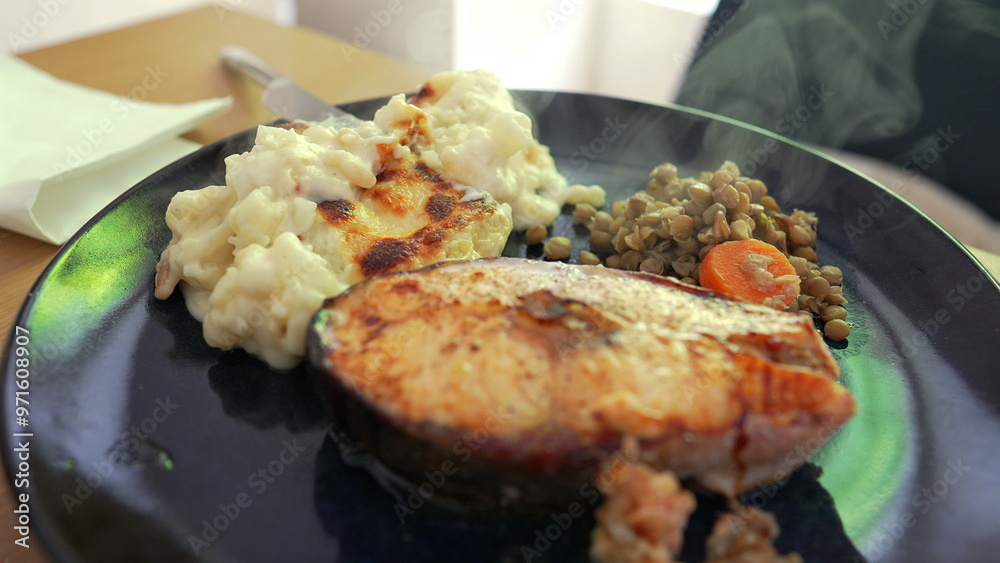 Grilled salmon steak served with creamy mashed potatoes and a side of sautéed lentils with carrots, showcasing a balanced and nutritious meal presentation Grilled salmon steak served with creamy mashed potatoes and a side of sautéed lentils with carrots, showcasing a balanced and nutritious meal presentation