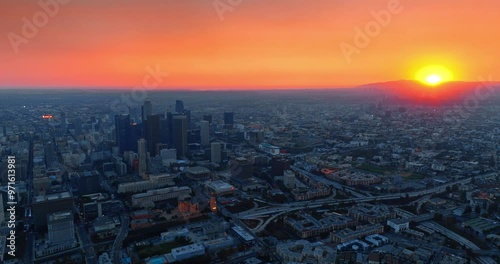 Sun hiding behind the mountain in gorgeous Los Angeles, California, the USA. Drone rising above the city view at sunset.