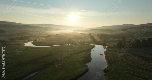 Flying over calm river in a misty valley