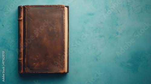 A vintage leather-bound book rests on a textured blue surface, suggesting a sense of history.