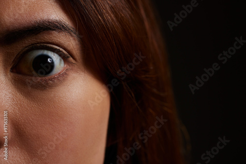 Woman, portrait and eye with shock in horror for fear, trauma or mental illness in asylum or studio on a black background. Closeup, face and scare with nightmare for spooky despair, paranoid or panic