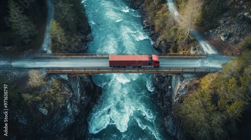 A red truck crosses a narrow bridge over a rushing river in a scenic landscape. photo