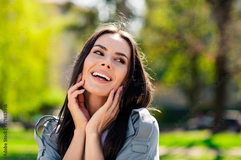 Portrait photo of beautiful young smiling hispanic attractive lady wearing gray coat town local park touching cheeks relaxed in nature Portrait photo of beautiful young smiling hispanic attractive lady wearing gray coat town local park touching cheeks relaxed in nature