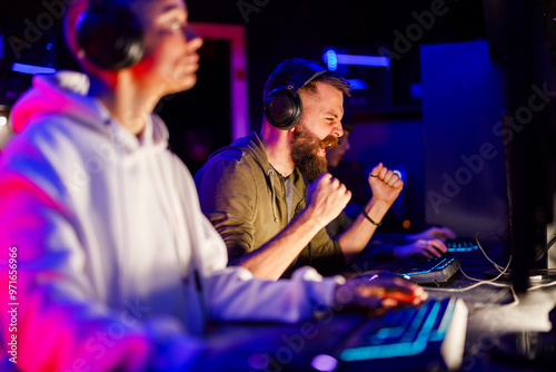 Fényképezés Gamer guy celebrating victory in video game while sitting in cybercafe