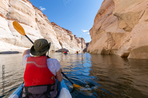 Back of young happy girl kayaking on lake powell with paddle and kayak and life vest on Antelope slot canyon in Arizona during summer