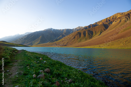 Chandratal lake, Moon Lake during Sunset with crystal clear water in between mountains surrounded by snowcapped mountains. photo