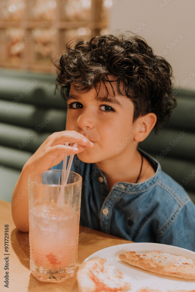 little boy eats pizza and drinks a cocktail in a pizzeria little boy eats pizza and drinks a cocktail in a pizzeria