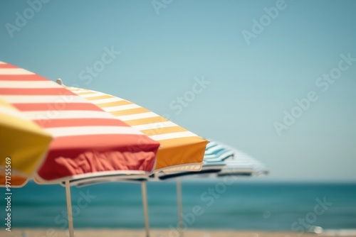 Colorful striped beach umbrellas, seen up close, set against the sand and sea..