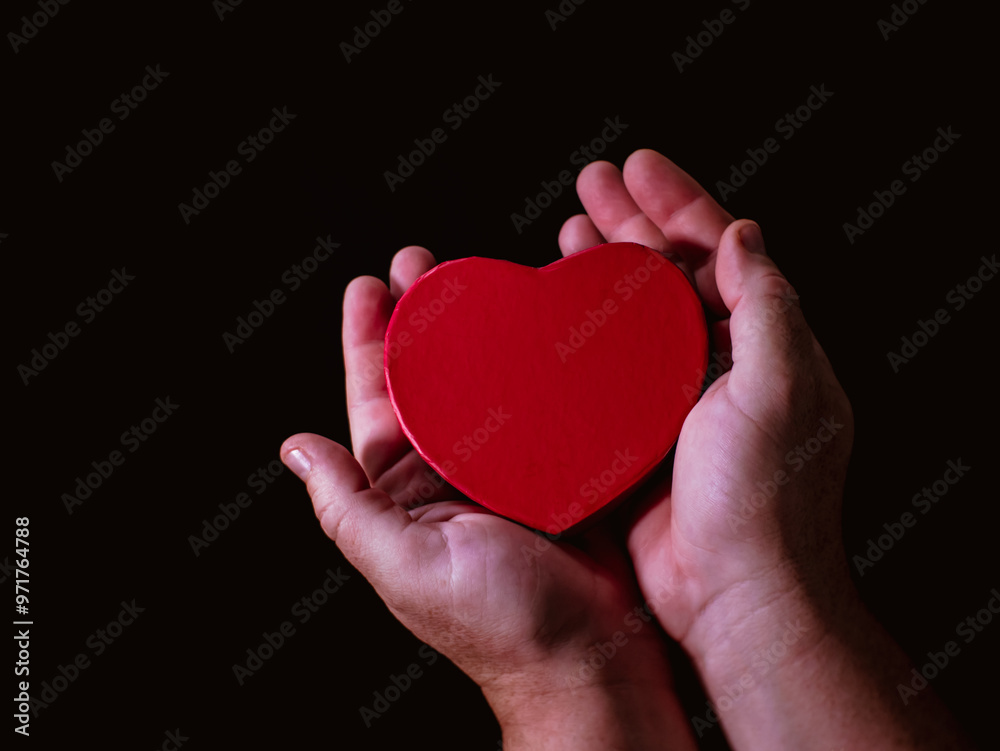 Hand holds a heart-shaped object Hand holds a heart-shaped object