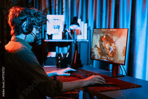 Host channel of young gaming streamer playing fighting Moba at battle arena game with multiplays team, wearing headphone on pc monitor with back side image at neon digital light modern room. Gusher. photo