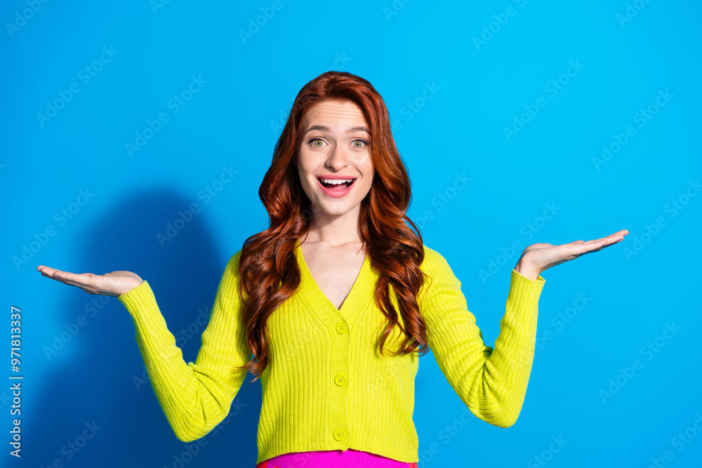 Photo portrait of pretty young girl compare hold excited empty space wear trendy yellow outfit isolated on blue color background Photo portrait of pretty young girl compare hold excited empty space wear trendy yellow outfit isolated on blue color background