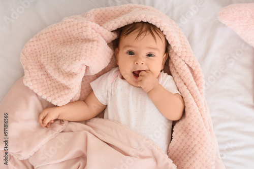 Cute little baby with pink plaid lying on bed, top view