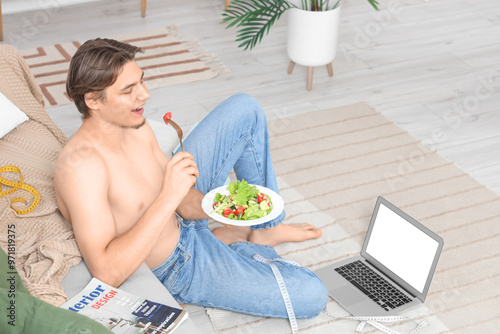 Young man eating vegetable salad at home. Weight loss concept