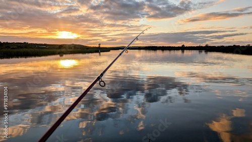 Hand holding fishing rod and reel, sunset fishing at Corrib river at Galway, Ireland, spinning, angling, catch and release, sport and leisure, nature background photo