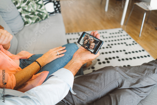 Senior couple resting on the couch while talking to family over video chat on the phone