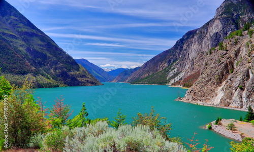 Seton Lake. Sunny day Mountain lake in the Rocky Mountain, light clouds in the blue sky, green forest on and bushes at the lake