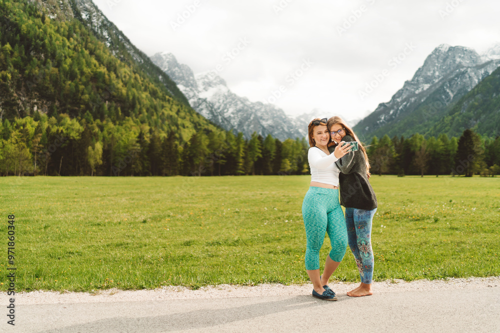 Happy friends taking selfie in the mountain valley in Alps. Enjoying nature, running, smiling, doing exercise on the grass field. Happy friends taking selfie in the mountain valley in Alps. Enjoying nature, running, smiling, doing exercise on the grass field.