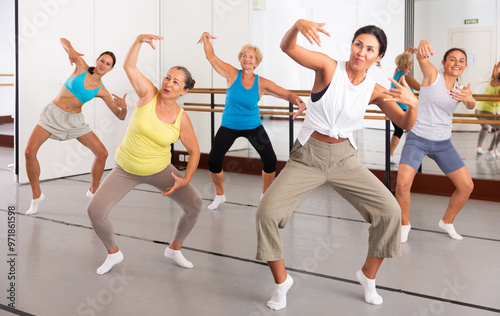 Active women engaged in dancing at a group training session in the studio practice modern energetic dance photo