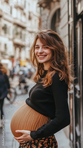 Radiant expectant mother in a black sweater and floral skirt cradles her belly, smiling joyfully on a charming European street. Her warmth illuminates the scene.