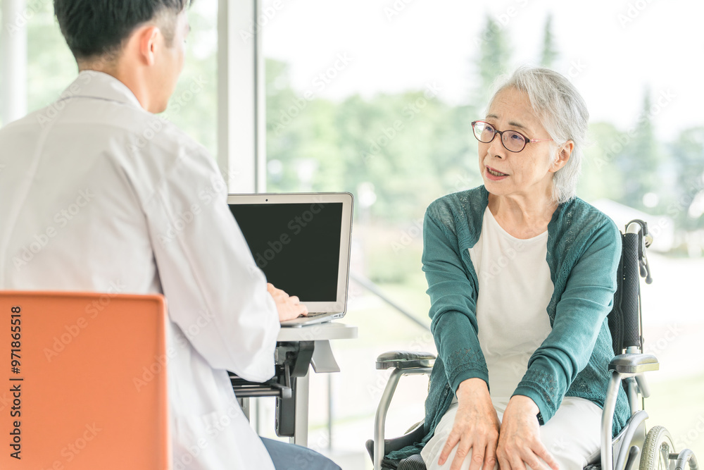 Obraz premium 病院・介護施設で医師に病状を伝えるシニア女性と問診する男性医師(診療・診察・人間ドック・健康診断)