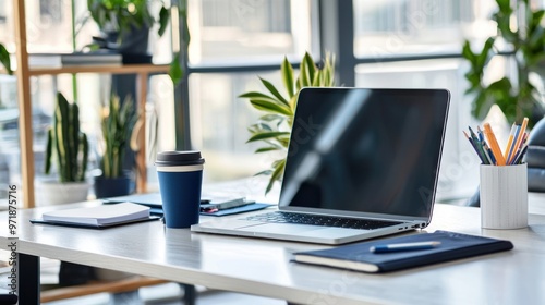 Modern office desk setup with a laptop computer, coffee cup, and various office supplies.