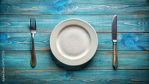 Vacant plate, clean cutlery, and a barren table spread a somber picture of a feast left unconsumed. photo