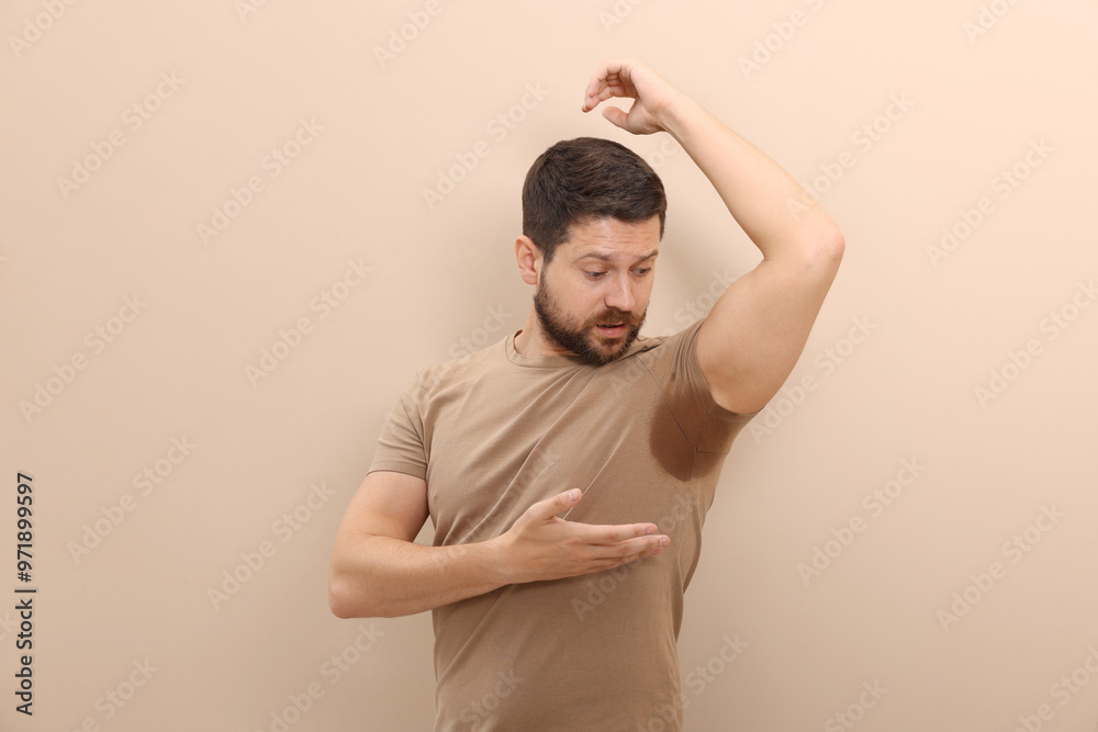 Emotional man in t-shirt before using deodorant on beige background Emotional man in t-shirt before using deodorant on beige background
