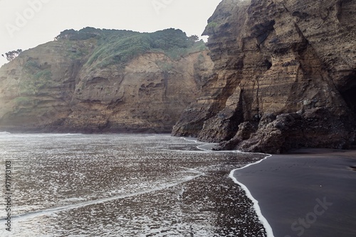 Rocky cliffs and water washing upto them. Piha, Auckland, New Zealand. photo