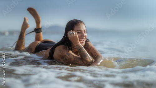 Εκτύπωση καμβά Candid photo of a tattooed girl on a surfboard laughing