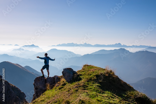 Silhouette of hiker man in alpine landscape of Gailtal Alps, Carinthia, Austria. Panoramic view of majestic hazy mountain ridges of Julian Alps, Karawanks, Carnic Alps. Peaceful tranquil atmosphere photo