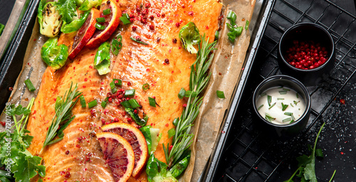 Cooked seafood on a black background. Baked salmon with onion, lemon, pomegranate juice