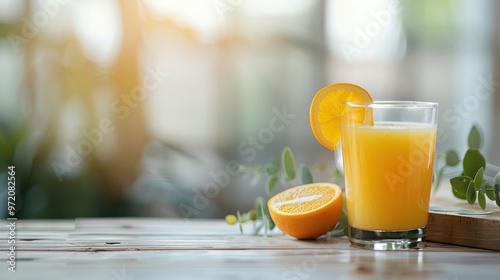 Refreshing glass of orange juice with slice, wooden table, bright sunny morning backdrop.